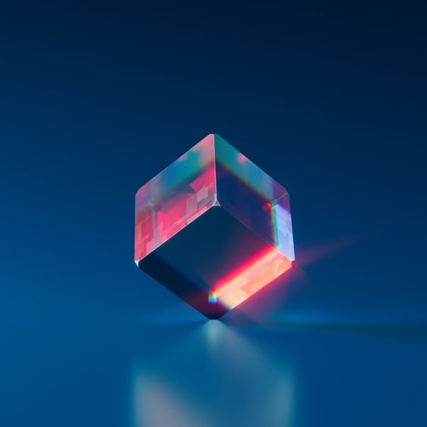 a multi-colored crystal cube standng on one point on a blue background